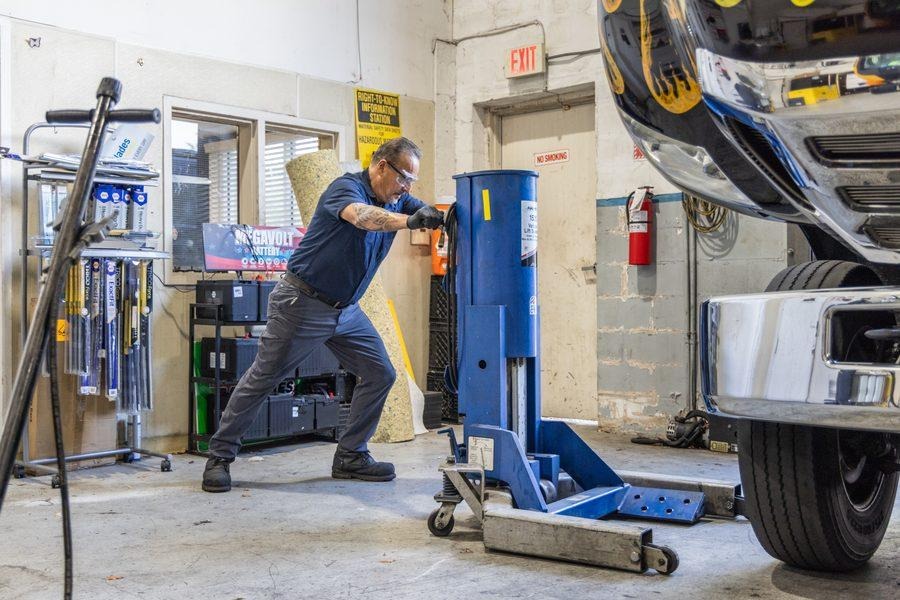 NH Repairs mechanic operating hydraulic jack under commercial truck